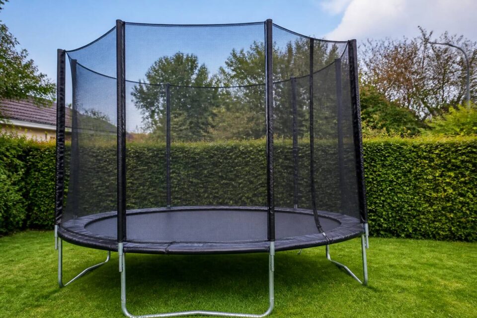 Trampoline met veiligheidsnet en randkussen in een tuin, klaar voor veilig gebruik